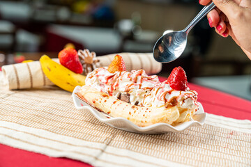 banana split is an American ice cream-based dessert consisting of a peeled banana cut in half lengthwise, and served with ice-cream and sauce between the two pieces.