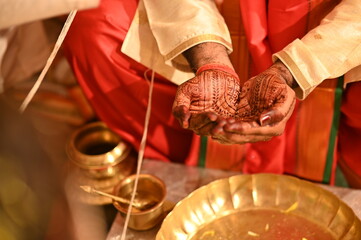 Water drops on the Indian groom hands. Plate with petals and water. Kanyadaan ceremony. Groom hands with mehendi. Marathi Wedding Rituals and Ceremony. Maharashtra. Indian Marriage 
