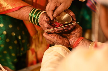 Father of the Bride drops water and petals on brides and grooms hands. Bride and groom holding hands of each other. Kanyadaan ceremony. Marathi Wedding Rituals. Maharashtra 