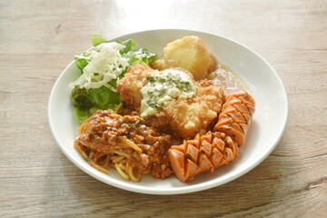 crispy fried chicken meat stuffed cheese with mash potato dressing gravy sauce and spaghetti and cabbage cos lettuce salad couple sausage on plate 