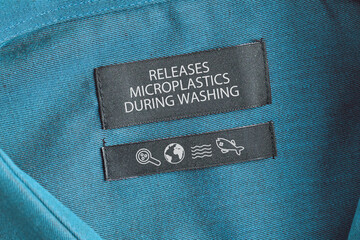 Clothing label saying 'Releases microplastics during washing'. Concept for synthetic clothing fiber...