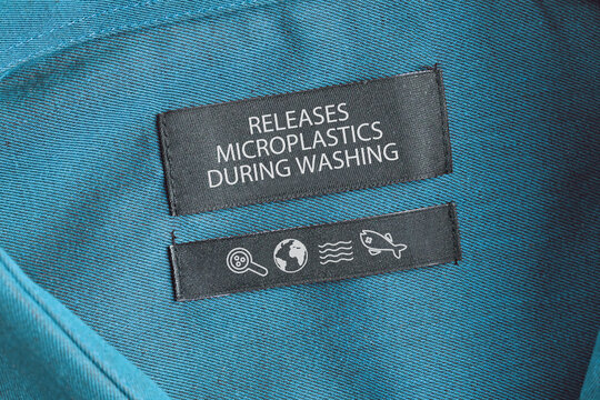 Clothing label saying 'Releases microplastics during washing'. Concept for synthetic clothing fiber pollution problem