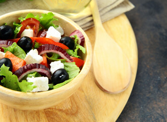 Greek salad with olives in a wooden bowl