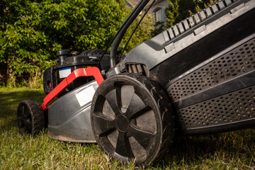  Concept of gardening, work, nature. Housework, gardening and country life. Home garden grass cutting woman mowing with lawn mower. Detail of lawn mower. Сutting grass in backyard.