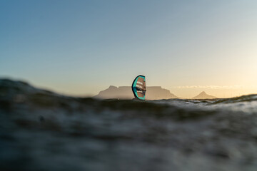 A man is wing foiling in-front of Table Mountain using handheld inflatable wings and hydrofoil...