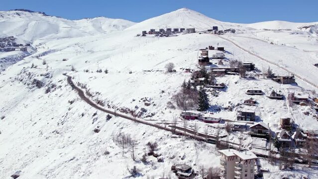 Aerial orbit establishing of snowy Farellones with El Colorado and La Parva ski resorts on a sunny day in the background, Chile