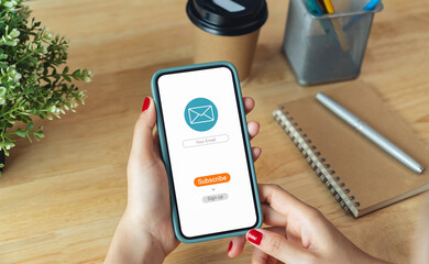Female hand holding smartphone and shows a digital screen of subscribe email notifications or sign...