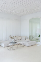 interior of a bright living room in a luxurious baroque style with white walls decorated with antique stucco