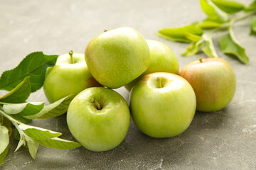 Ripe green apples with green leaves on grey background