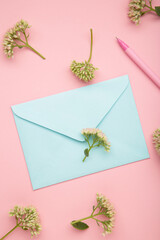 Composition with envelope and beautiful flowers on pink background. Vertical photo