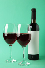 Wine bottle and wine glass on mint background. Vertical photo