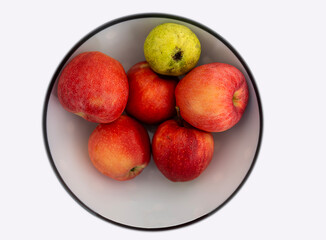 Red apples in white ceramic plate, macro shot, isolated on white background.