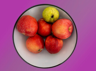 Red apples in white ceramic plate, macro shot, isolated on colored background.