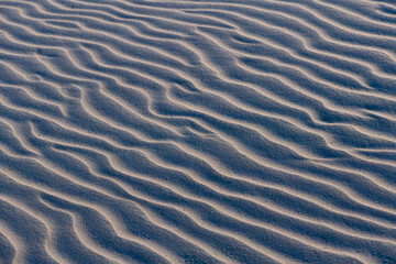 Sand structures with ripples at low tide on the beach of Juist island, Germany in National Park “Wattenmeer“. Natural background pattern formed by current and wind. High contrast with selective focus.
