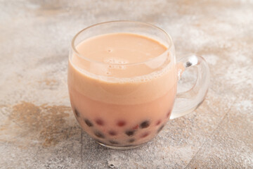 Bubble tea with pistachio and caramel in glass on brown concrete, Side view.
