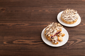 Tartlets with meringue cream and cup of coffee on brown wooden, side view, copy space.