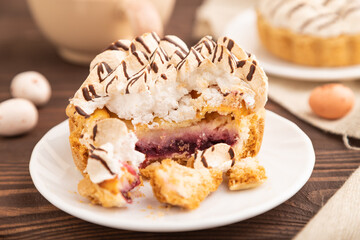 Tartlets with meringue cream and cup of coffee on brown wooden, side view, selective focus.