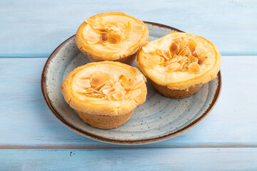 Traditional portuguese cakes pasteis de nata, custard small pies on blue wooden. Side view.