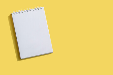 Opened notepad on a yellow background. Composition of writing to-dos for the day. The notebook lies on a plain background with space for writing. 