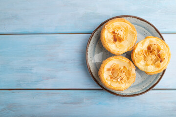 Traditional portuguese cakes pasteis de nata, custard small pies on blue wooden. Top view, copy space.
