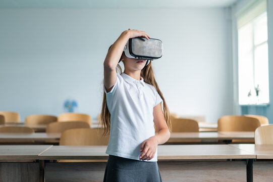 Caucasian schoolgirl wearing virtual reality glasses in the classroom. 