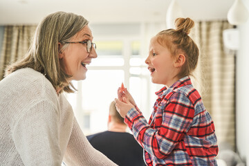 Cheerful mature woman in eyeglasses having fun with her granddaughter