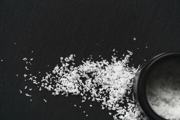 Organic sea white salt and a jar on a black slate background. Concept of cooking natural healthy food