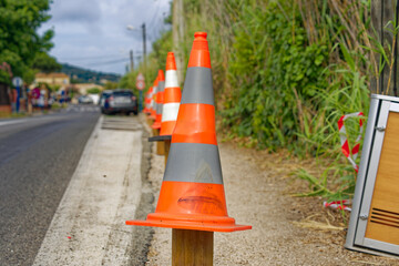 Pylons at road construction site with installation of wooden crash barrier on a bleu cloudy late...