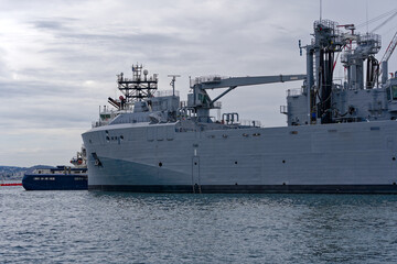 Moored supply warship and tanker of French Navy at Toulon Naval Base on a cloudy spring day. Photo taken June 9th, 2023, Toulon, France.