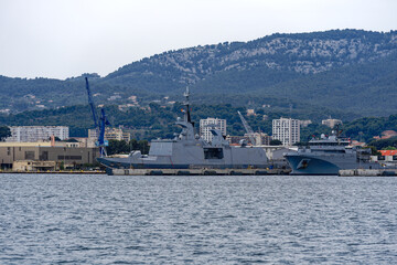 Moored warships at French Navy Naval Base at City of Toulon on a cloudy late spring day. Photo taken June 9th, 2023, Toulon, France.