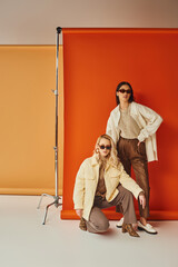 fashion and style, interracial models in sunglasses and outerwear posing in studio, fall colors