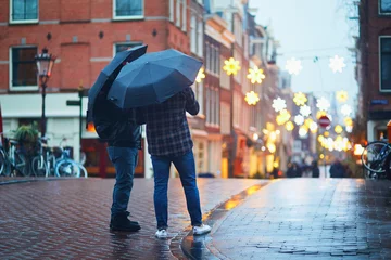 Rolgordijnen Two men with umbrellas on a street on a rainy winter day in Amsterdam, the Netherlands © Ekaterina Pokrovsky