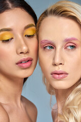 multicultural models with bold eye makeup posing together on blue backdrop, expressive eyes
