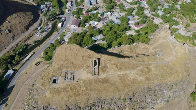 Tilt down aerial shot of Bjni Fortress and village on sunny summer day. Kotayk Province, Armenia.