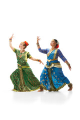 Naklejka premium Sattriya dance. Women, in beautiful traditional indian dresses dancing against white studio background. Concept of beauty, fashion, India, traditions, lifestyle, choreography, art. Ad