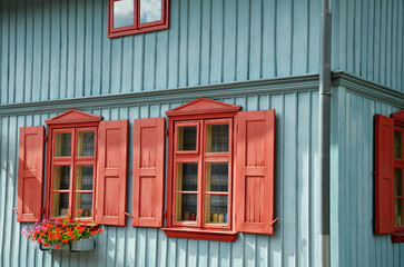 Restored old blue wooden house with red shutters