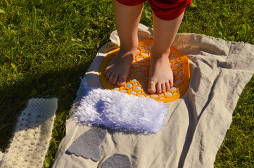 Children's feet walk on an orthopedic massage diy mat with surfaces of various shapes and...