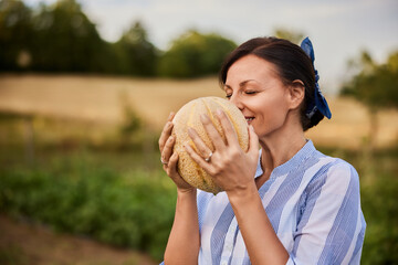 Close-up of a woman smelling the melon from her garden.
