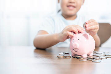 A little girl saving money in piggy bank
