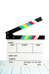 The Clapperboard or movie slate on blue wooden floor with white background. It use in video production and film industry.