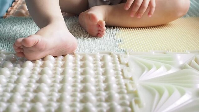 Toddler baby foots on a medical orthopedic colorful massage mat. 