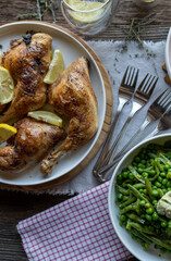Baked chicken legs with green vegetables on wooden table