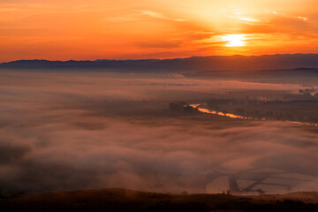 Aerial view of the sunrise over the valley in beautiful early morning mist in the highlands. Low clouds and fog cover the sleeping meadow. Hills valley mists landscape. Serene moment in rural area