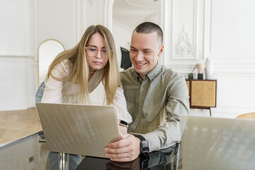 A woman and a man are friends in the office. Confident creative people work online on a project. Use a laptop computer on the desktop.