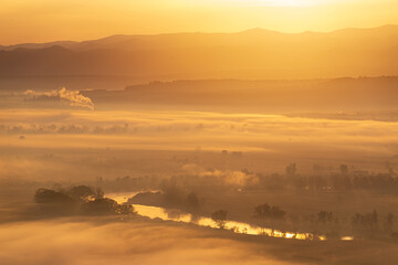 Aerial view of the sunrise over the valley in beautiful early morning mist in the highlands. Low clouds and fog cover the sleeping meadow. Hills valley mists landscape. Serene moment in rural area