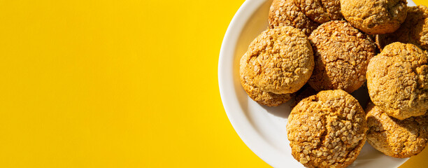Australian traditional cookies - Anzac. Anzac biscuits Made from rolled oats and coconut. Cookies in a plate on a yellow background, with hard shadows. Banner