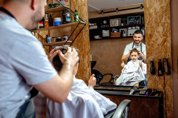 Thumbs up for a new haircut. Boy in barbershop. Satisfied with new haircut.