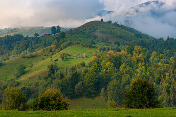 Fototapeta na wymiar Rural idyllic landscape of the small villages in the Rucar-Bran mountain area, Brasov, Romania, scattered on the wooded hills, with the Bucegi mountains in the background, in wonderful springtime day