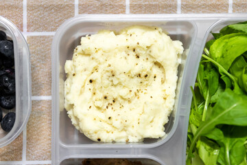 Mashed potatoes with butter and spices in lunch box container. 