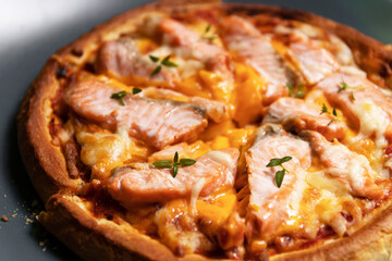 Delicious gourmet pizza with salmon on board with black table background. Homemade delicious pizza.